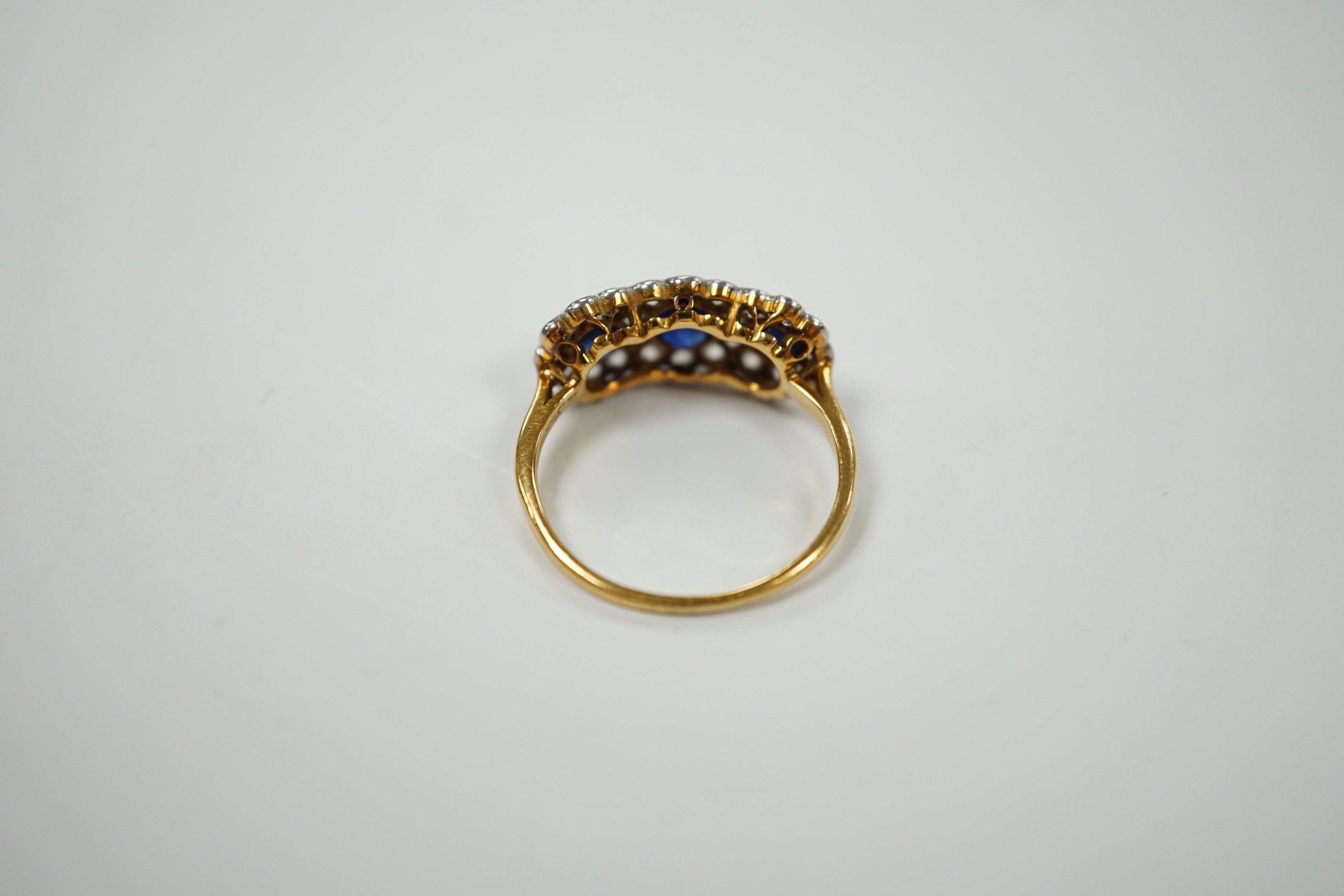 A yellow metal and millegrain set sapphire and diamond triple cluster ring, size K/L, gross weight 2.5 grams.